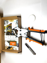 Garden shears with orange handles next to a cardboard box on a white background