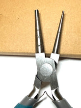 Metal pliers with measurement markings on a cardboard background