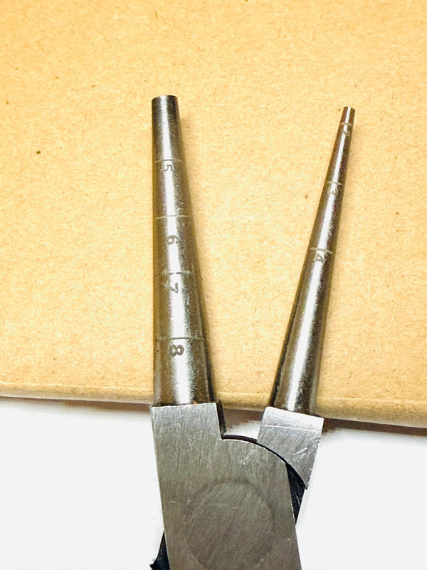 Metal pliers with measurement markings on a wooden background